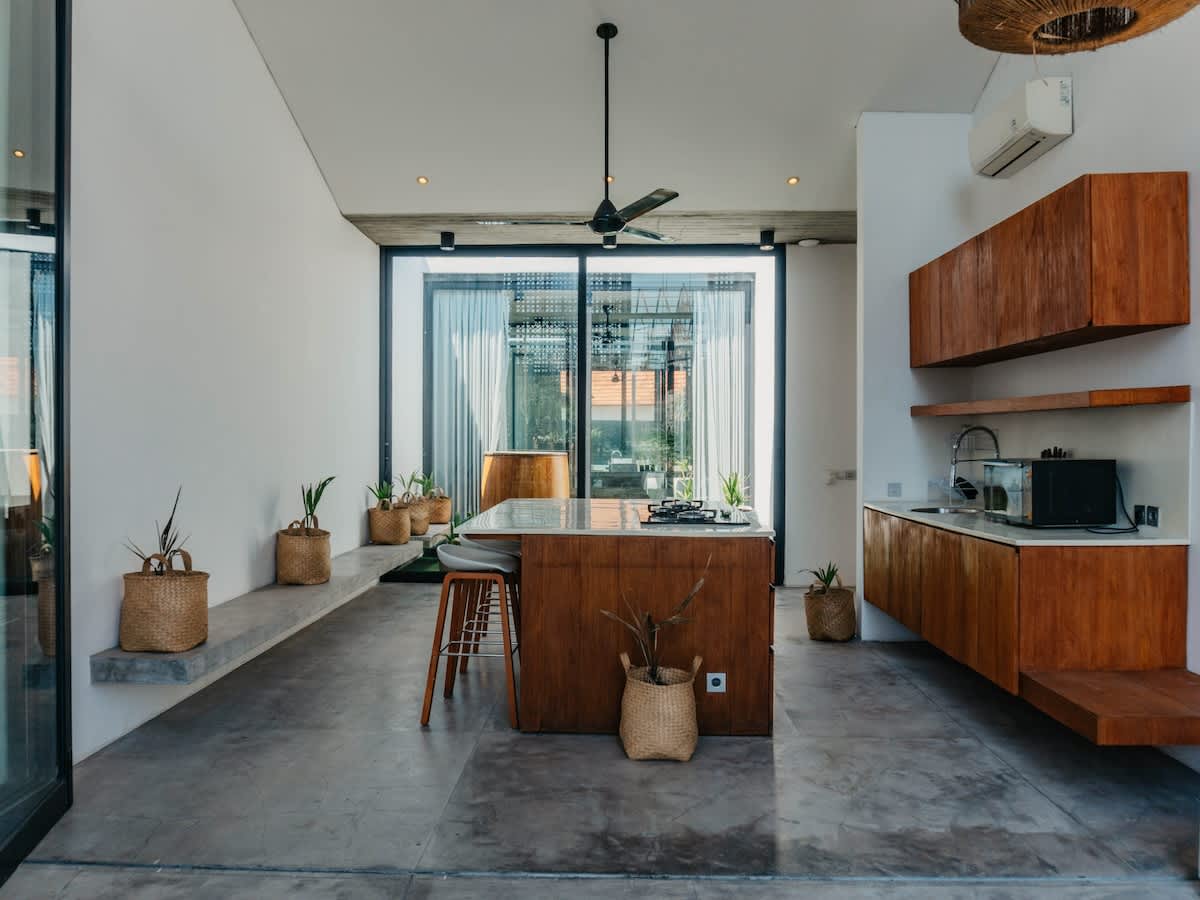 Bright, minimalist kitchen with natural wood, polished concrete floors and indoor–outdoor flow. Fully equipped for cooking, with an island bench perfect for relaxed meals in a calm, tropical setting.